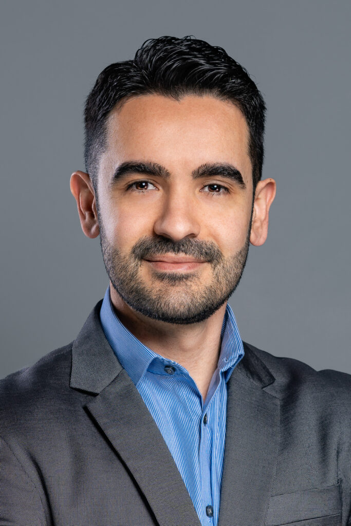 Professional studio headshot with a gray backdrop.