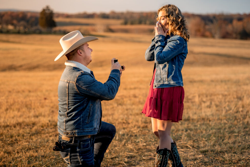 A man proposes to his fiancee during their cowboy inspired sunset engagement photoshoot at Manassas Battlefield Park in Virginia.