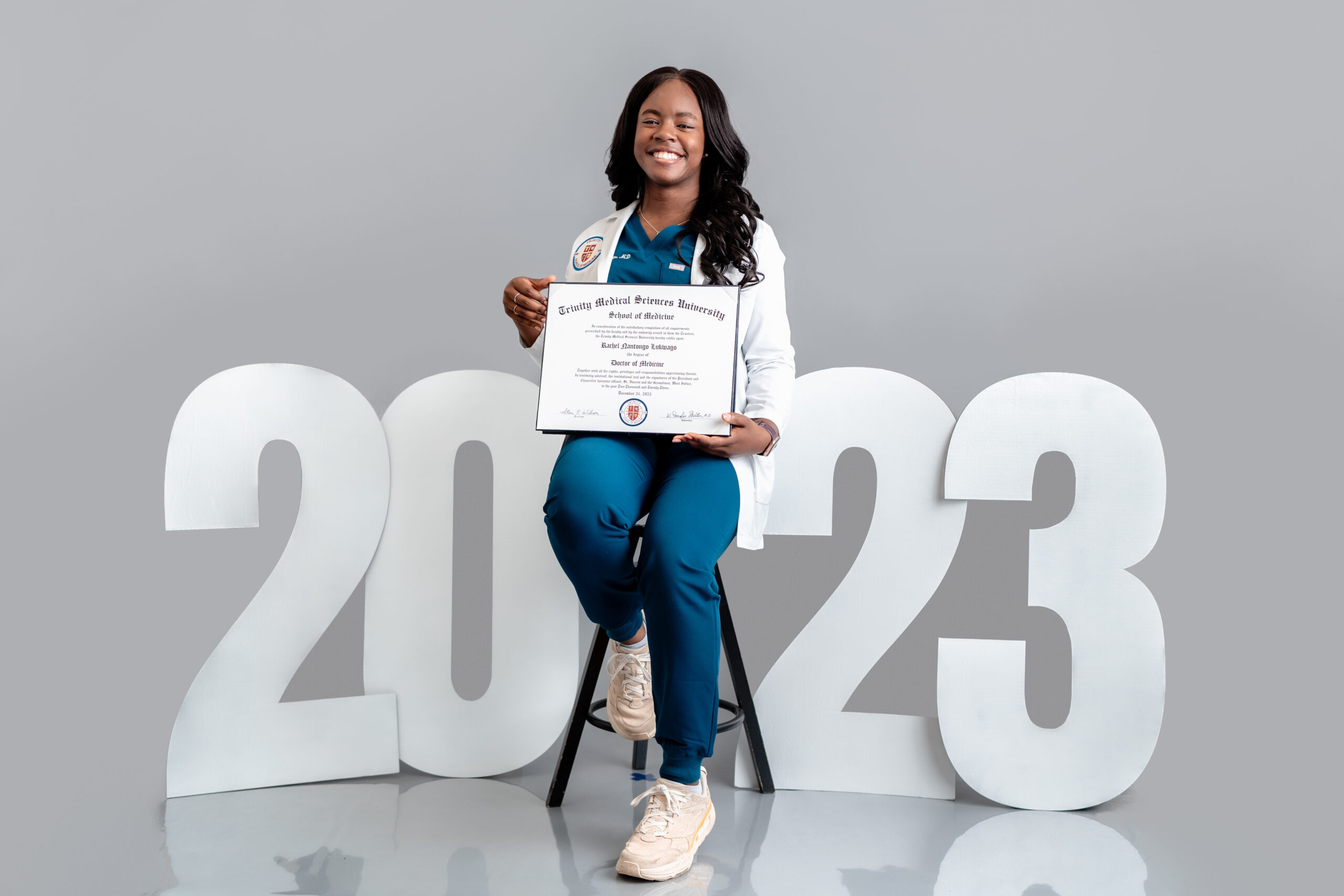 A medical graduate school student holds up her diploma in front of the year she graduated.