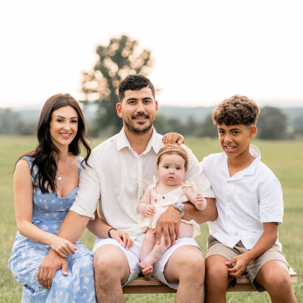 Family of four smiling and posing at Manassas Battlefield Park during sunset.